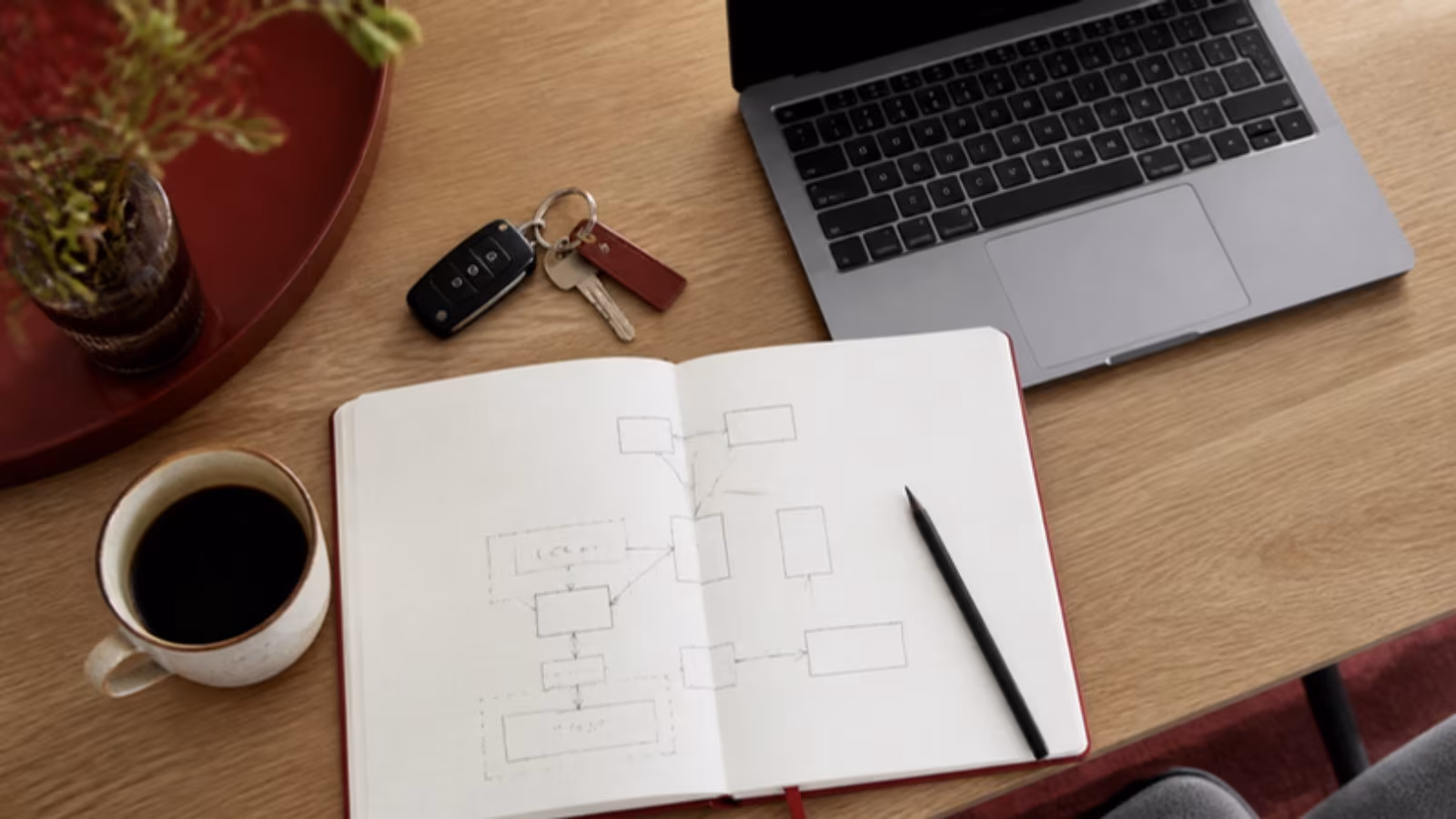 Klíče od auta, zápisník s náčrtem a notebook na dubovém stole
