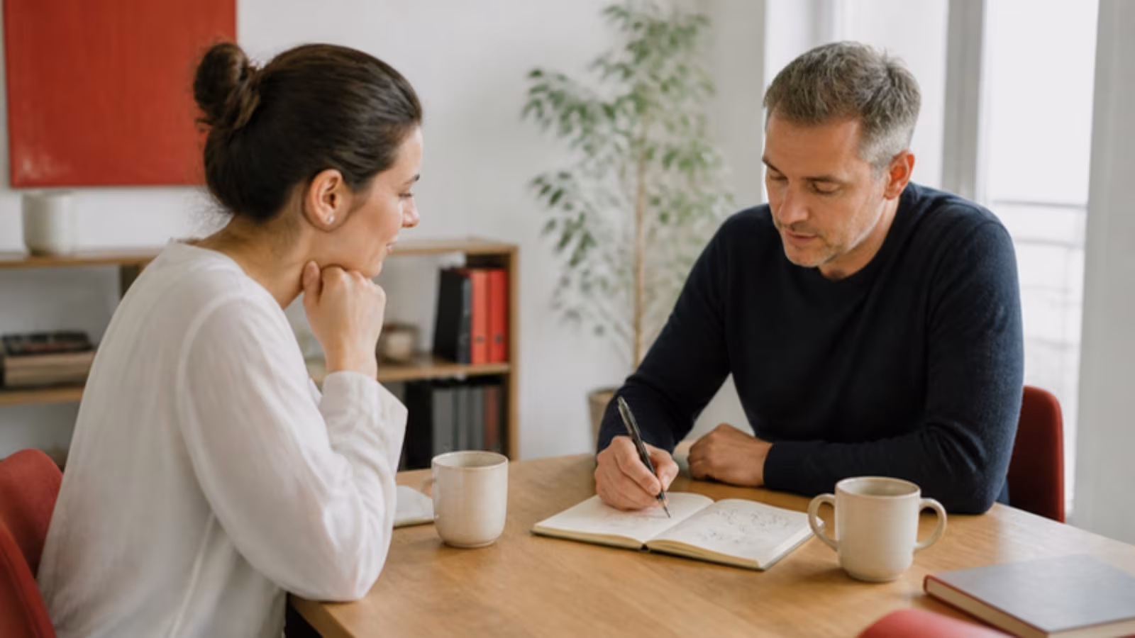 Mentor kreslí plán do zápisníku, klientka pozorně poslouchá